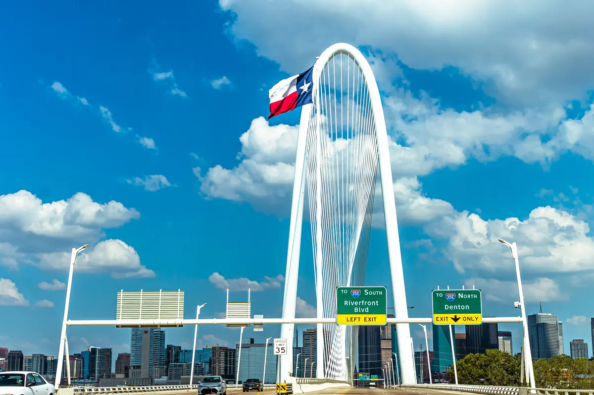 Margaret Hunt Hill Bridge with the Texas flag and the Dallas skyline