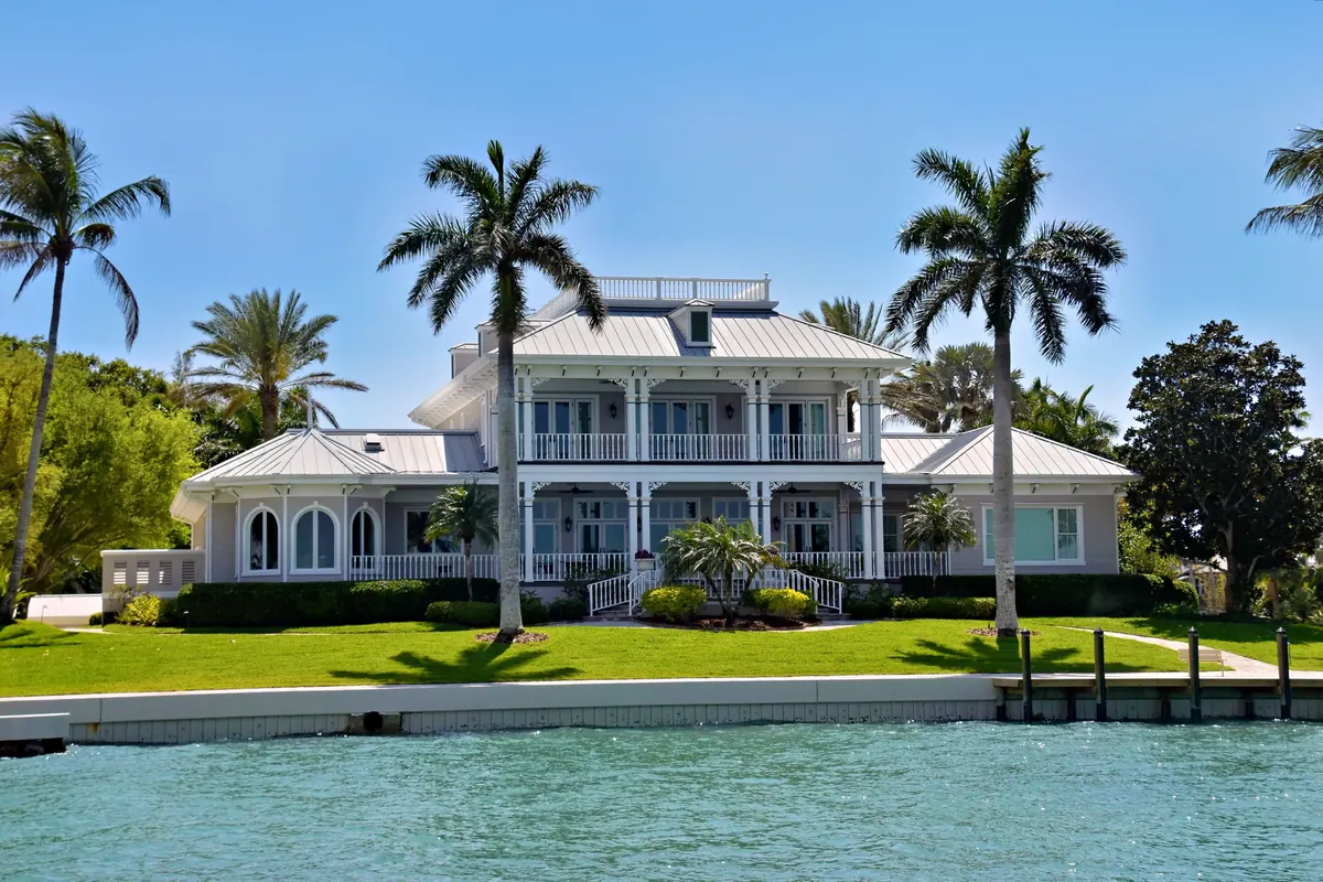 Two-story waterfront home with palm trees and a seawall in Florida